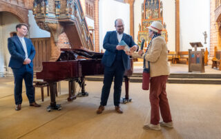 Uschi Becker überreicht Tom Kessler den Band Töster Blicke, Kai Schöneweiß schaut zu.